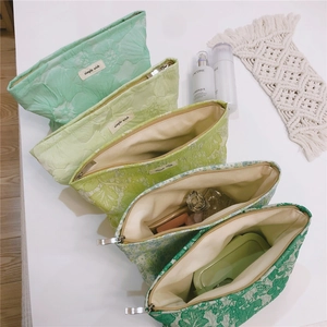 Flat lay of multiple green jacquard floral canvas makeup bags with metal zippers
