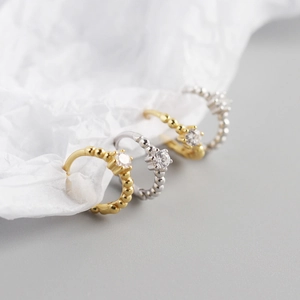 Detail of gold and silver beaded hoop earrings featuring sparkling inset crystals on white paper