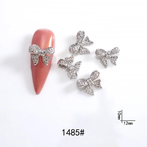 Macro detail of silver bow tie nail art charm with rhinestones and size dimensions