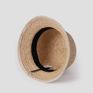 Detail showing the inner black sweatband and white fringe brim of the raffia sun hat