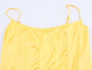 Detailed close-up of yellow satin dress bodice with delicate thin straps and stitching