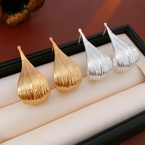 Macro shot of gold and silver plated leaf-shaped textured earrings in a black gift box