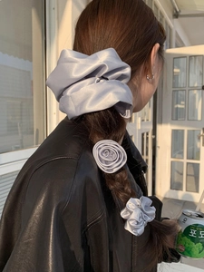 Close-up of elegant grey satin scrunchie set with rose flower accessory in hair
