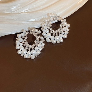 Detailed macro view of silver hoop earrings featuring pearls and sparkling rhinestones