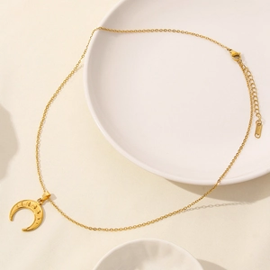 Detail view of the polished 18K gold-plated crescent moon pendant on a stainless steel chain