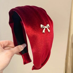 Close-up of a burgundy velvet headband featuring a gold metal hollow bow ornament