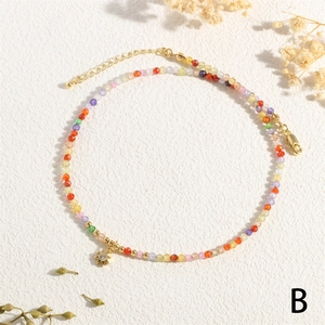 Detail of colorful faceted bead necklace with gold star pendant on textured background