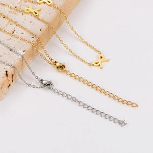 Detail view of gold and silver bow necklaces on a stone plate with lobster clasps