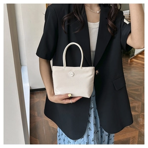Détail du sac seau en nylon crème avec poignée ronde et boucle décorative logo M