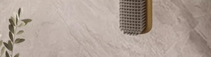 Close-up of wooden handle cleaning brush with dense grey bristles against stone wall