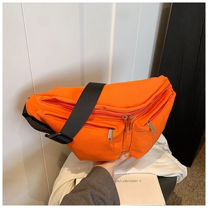 Detail view of bright orange canvas crossbody bag with multiple zippers and black strap