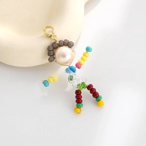 Detailed macro of a handmade colorful beaded doll pendant with a gold lobster clasp