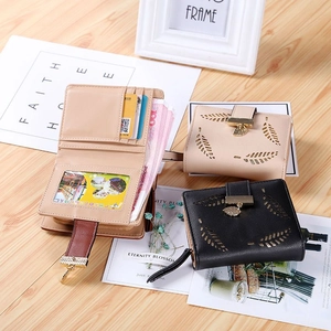 Women's hollow leaf pattern PU leather wallet with metallic pendant on wooden background