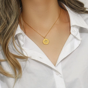 Close-up of 18K gold plated necklace featuring an eight-pointed star disc pendant
