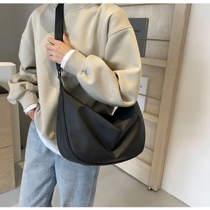 Model wearing a large black nylon crossbody dumpling bag showing a stylish casual fit