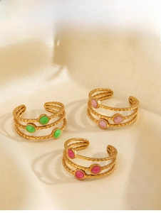 Detailed view of triple-layered gold rings with green, pink, and rose red gemstones