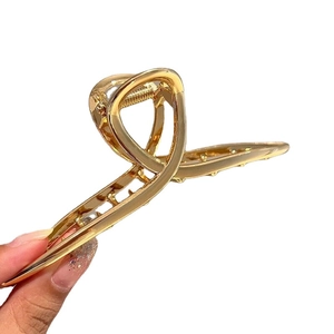 Large golden metal shark hair claw clip with minimalist cross-wrapped design for women