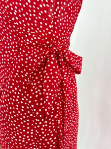 Detailed view of red polka dot dress featuring a waist tie bow and ruffled texture