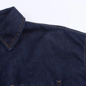 Détail de veste en jean bleu foncé avec coutures orange contrastées et texture de tissu