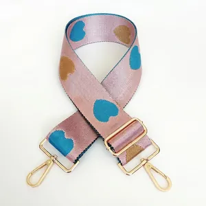Close-up of pink jacquard bag strap with heart patterns and golden rotating metal hooks