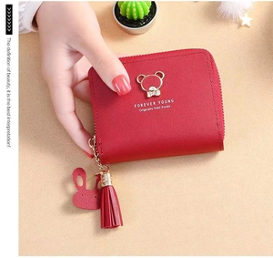 Detail of red faux leather wallet with gold bear ornament, tassel, and zipper closure