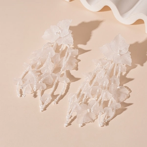 Close-up of white acrylic flower tassel earrings with frosted petals and beaded drops