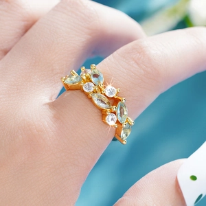 Close-up of a gold leaf ring with marquise-cut light blue and round white gemstones