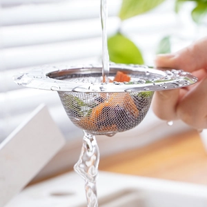 Stainless steel kitchen sink strainer filtering food scraps under running water