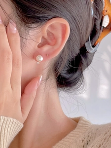 Close-up of elegant pearl stud earrings with zircon accent on model for a minimal look