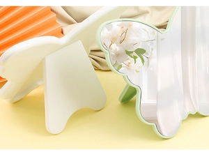Detailed view of white and light green butterfly-shaped makeup mirrors with foldable stands