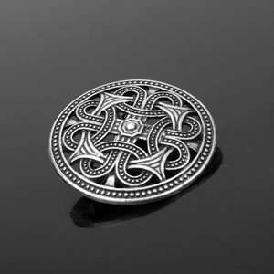 Macro detail of antique silver Viking shield brooch with intricate Celtic knot patterns
