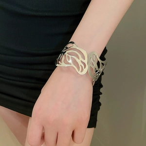 Detail of hollow leaf pattern metal open cuff bracelet worn on female model wrist
