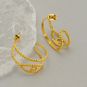 Golden geometric hollow earrings with textured beads on ice crystal prop background