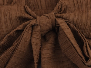 Macro shot of brown crinkle fabric featuring a delicate tie-knot and smocked texture