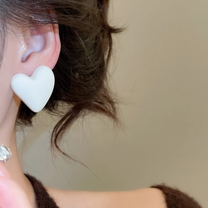 Close-up of a model wearing a minimalist white heart-shaped acrylic earring