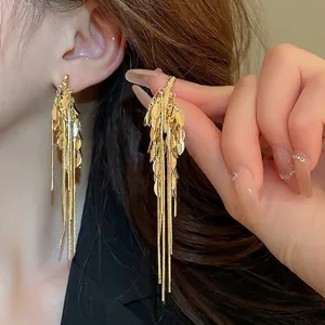 Elegant gold tassel earrings with leaf sequins and long metal chains on model