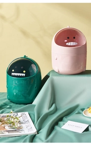 Close-up of cute dinosaur desktop trash cans in pink and green with clear lids