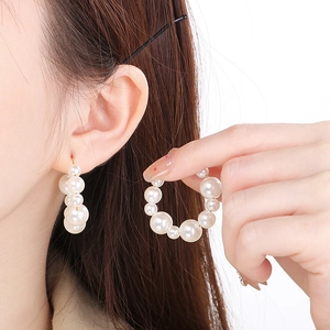 Detailed shot of large U-shaped pearl hoop earrings featuring multi-size white pearls
