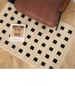 Detailed top view of checkered pattern rug on light wood floor next to leather armchair