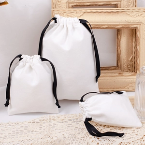 Three white cotton drawstring bags in various sizes displayed on a lace tablecloth