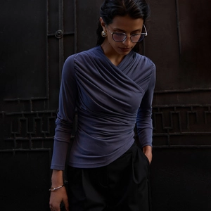 Close-up of elegant v-neck pleated details and draping fabric on a long-sleeve purple top