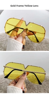 Detail of oversized gold metal sunglasses with yellow lenses and V-shaped nose bridge