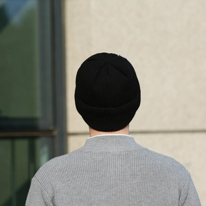 Outdoor back view of a minimalist black ribbed knit beanie for men with subtle embroidery