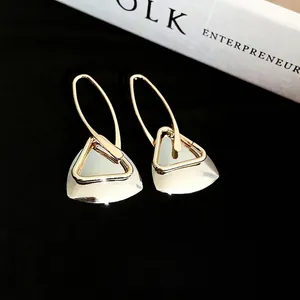 Minimalist gold hollow triangle earrings with semi-transparent fan charm on black background