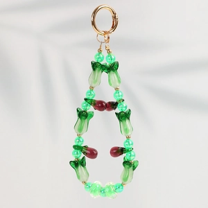 Détail d'un pendentif fait main avec perles en verre rouge et vert et anneau doré