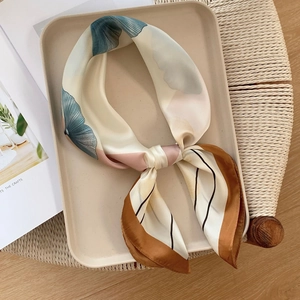 Detail of silk square scarf showing green ginkgo leaf pattern and silky smooth texture