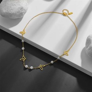 Golden butterfly and pearl hollow pendant necklace displayed on artistic stone pedestals