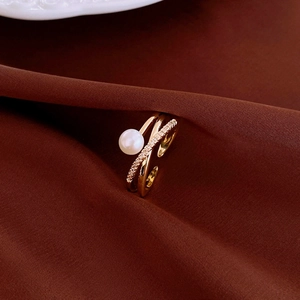 Detail of gold-plated crossover ring featuring a white pearl and sparkling pavé diamonds