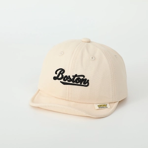 Detailed close-up of the beige cotton cap with black Boston embroidery and a yellow side label