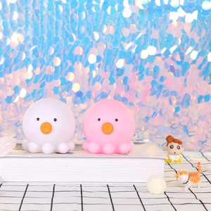 Close-up of cute pink and white octopus night lights on a dreamy sparkling blue background